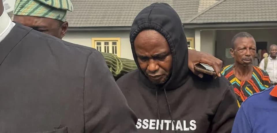 Man wearing hoodie surrounded by people outside building