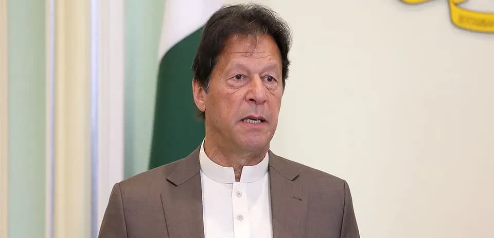 Man speaking at a podium with flags in background