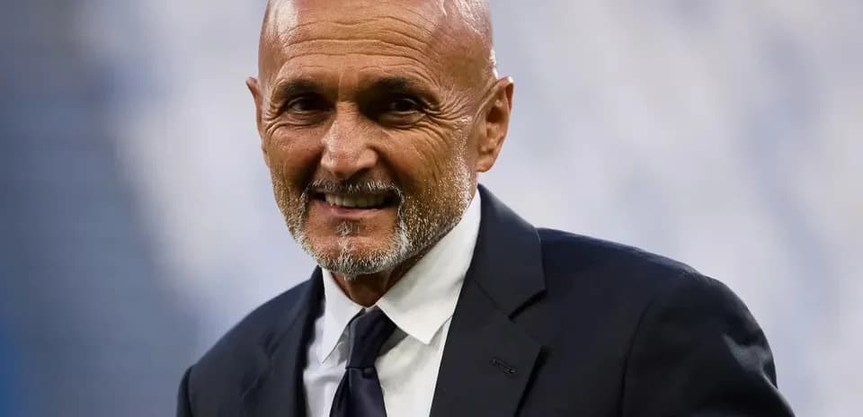 Coach smiling in a formal suit at stadium
