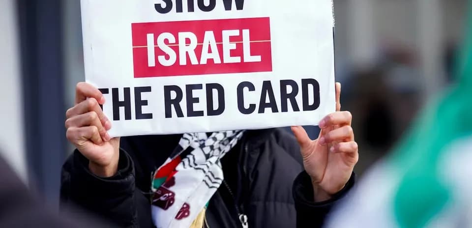 Protester holding sign reading 'Show Israel the red card'