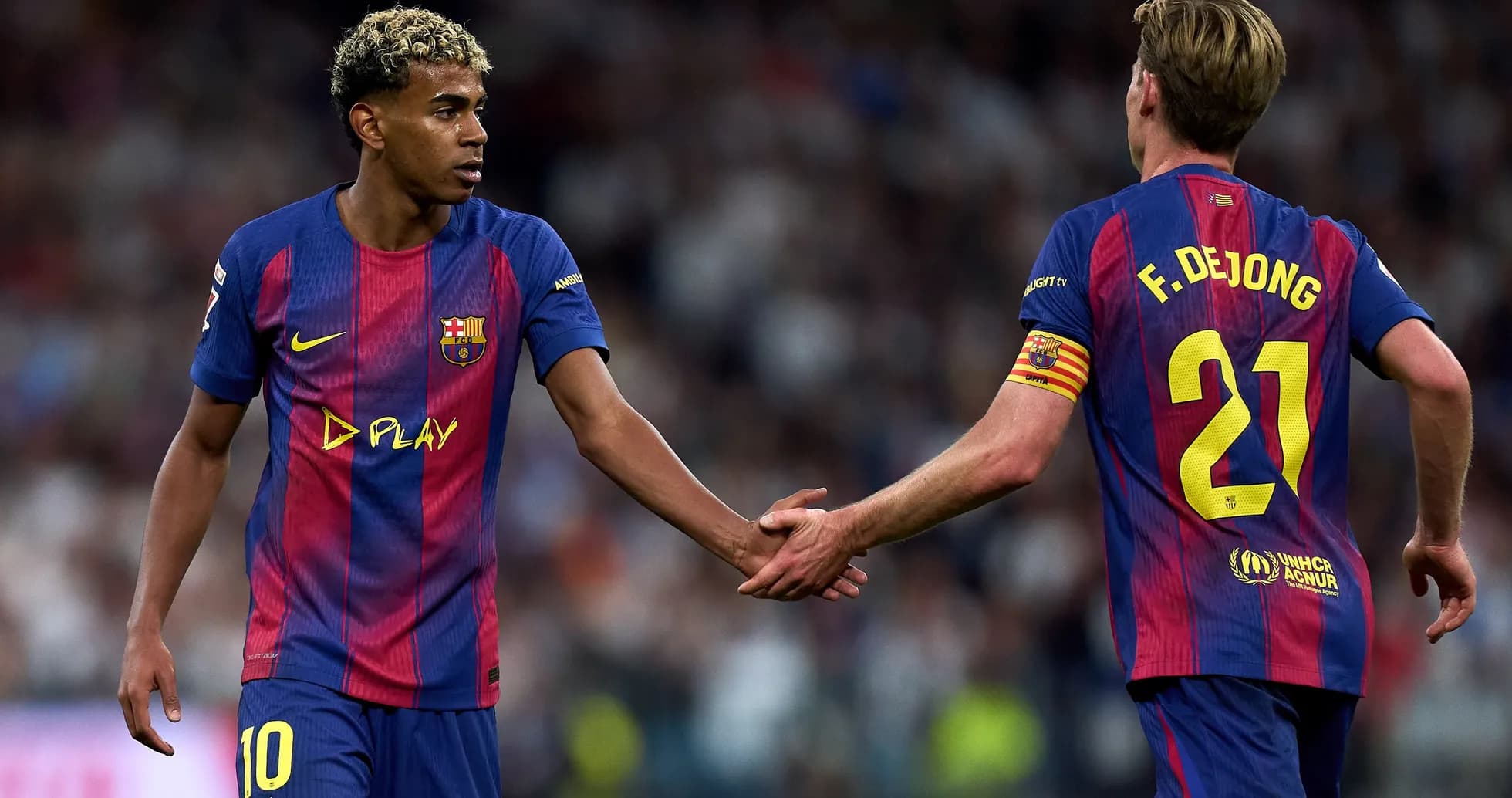 Two FC Barcelona players shaking hands on pitch