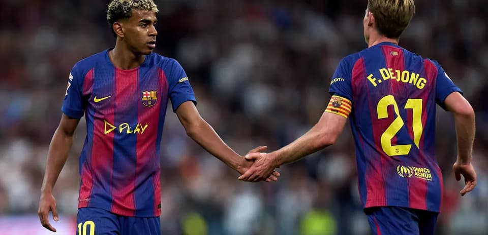 Two FC Barcelona players shaking hands on pitch