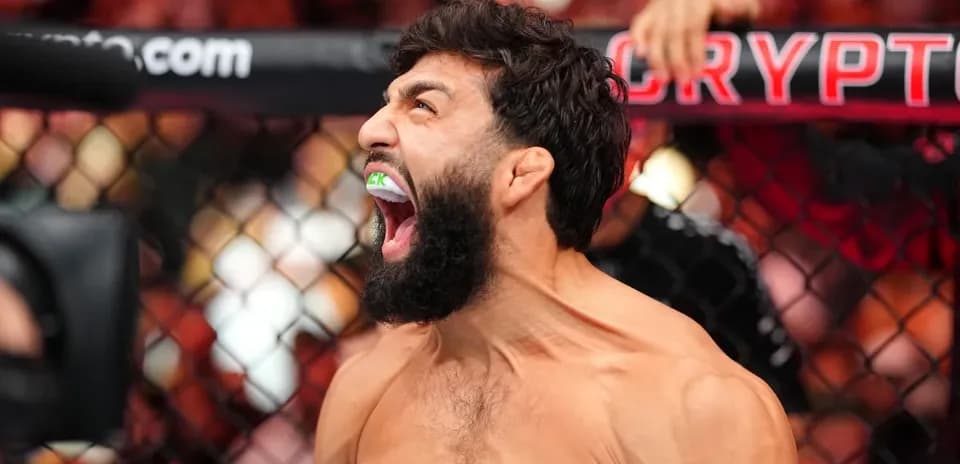 Fighter celebrating with mouthguard in MMA cage