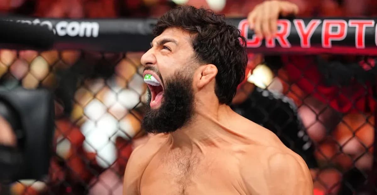 Fighter celebrating with mouthguard in MMA cage