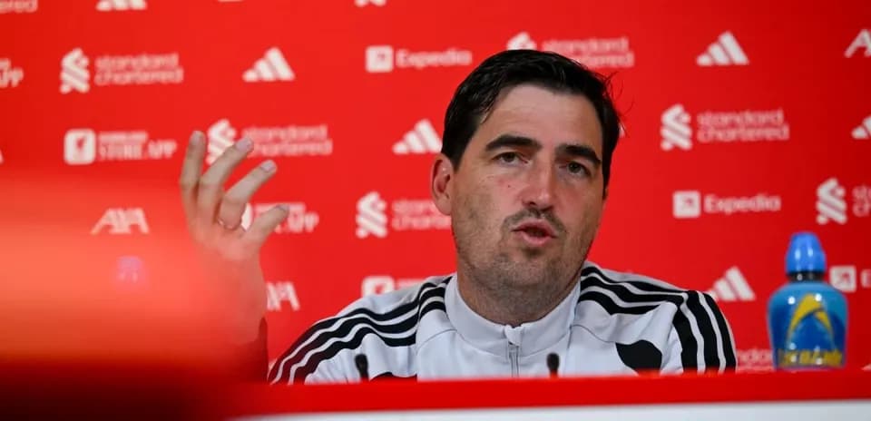 Manager speaking at press conference with red backdrop