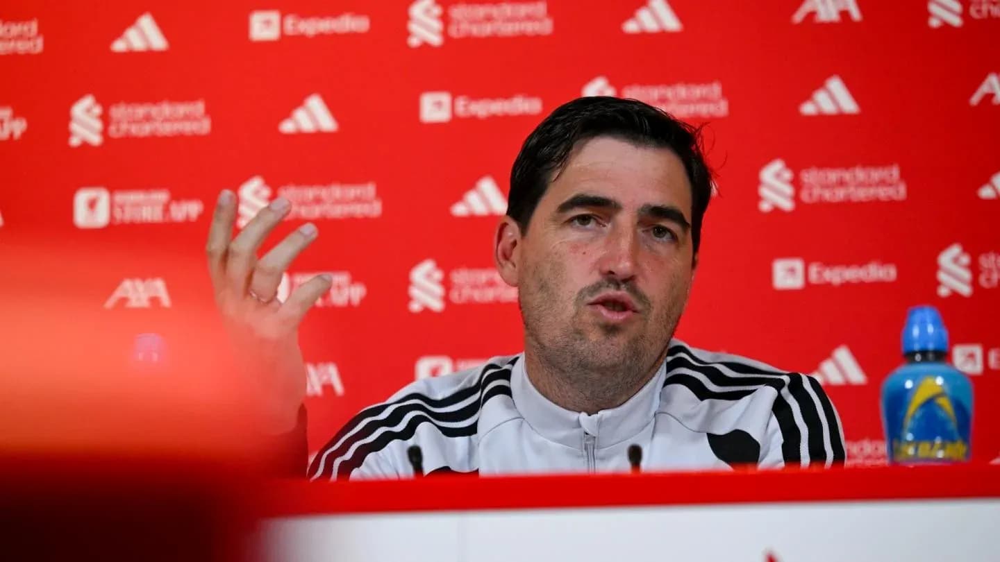 Manager speaking at press conference with red backdrop