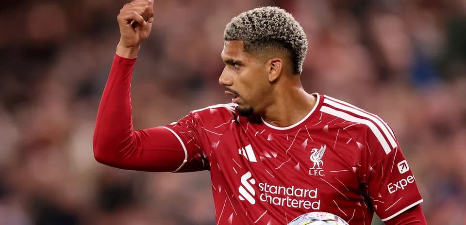 Player gesturing during match wearing Liverpool jersey