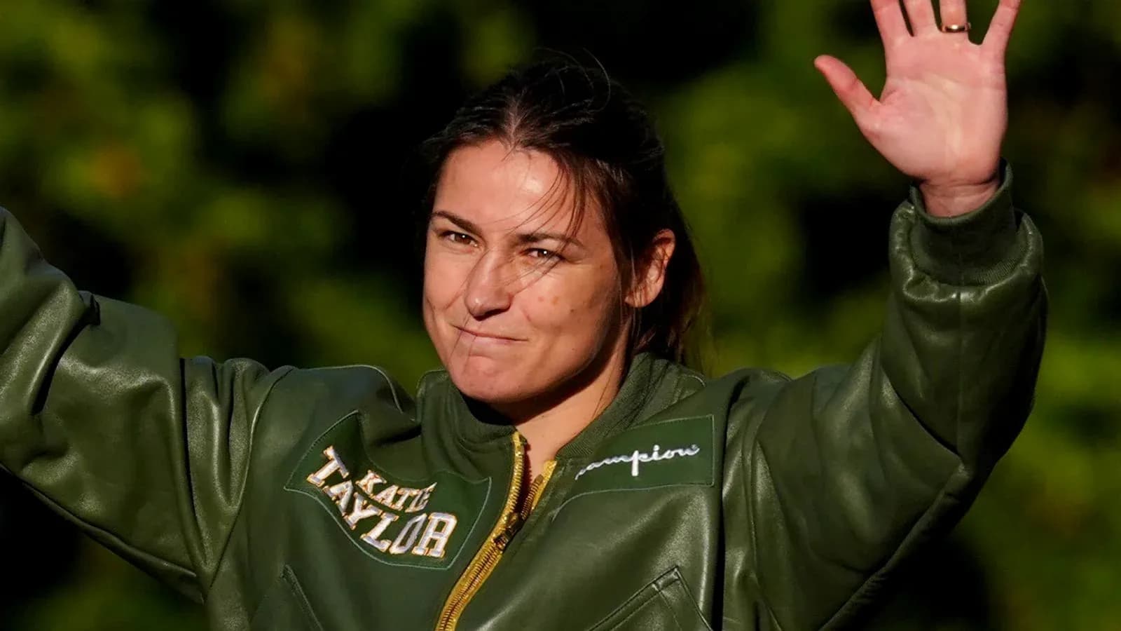 Athlete waving while wearing a green jacket