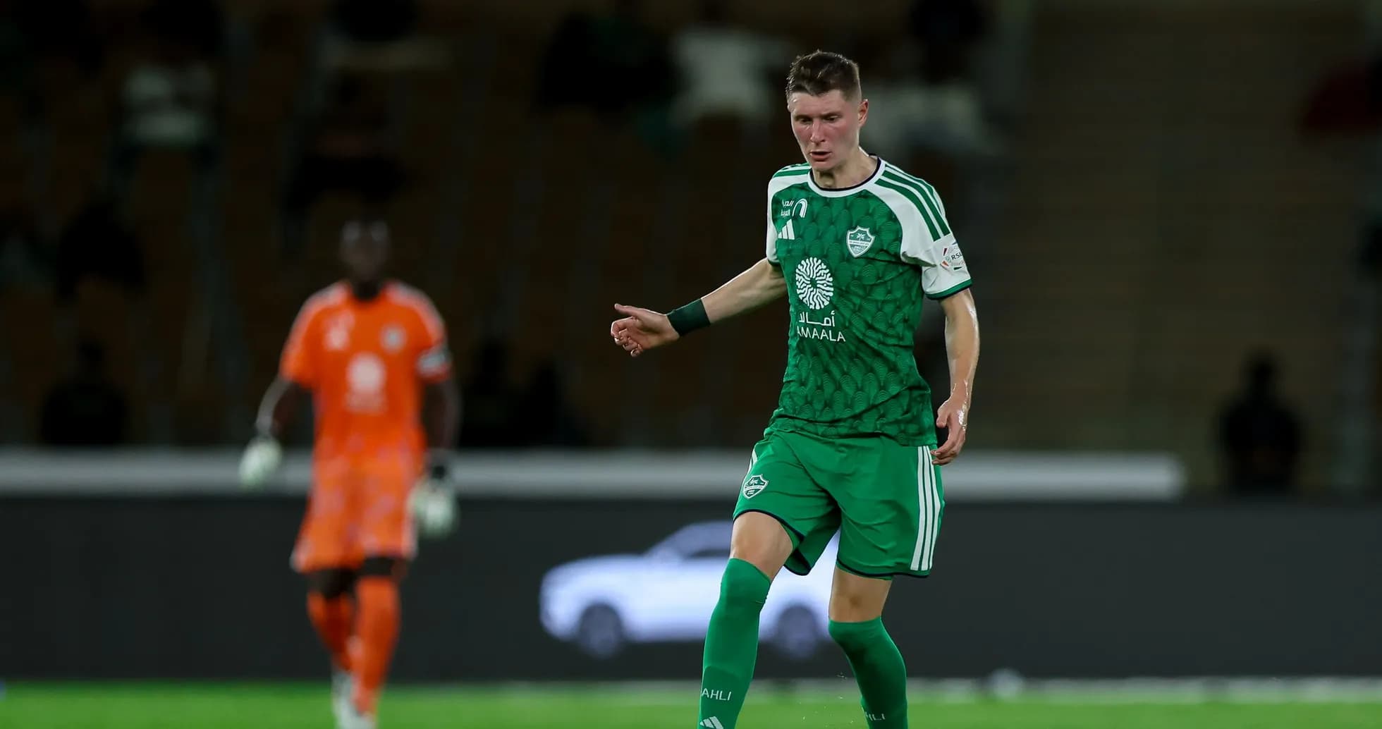 Player in green kit dribbling the ball during match