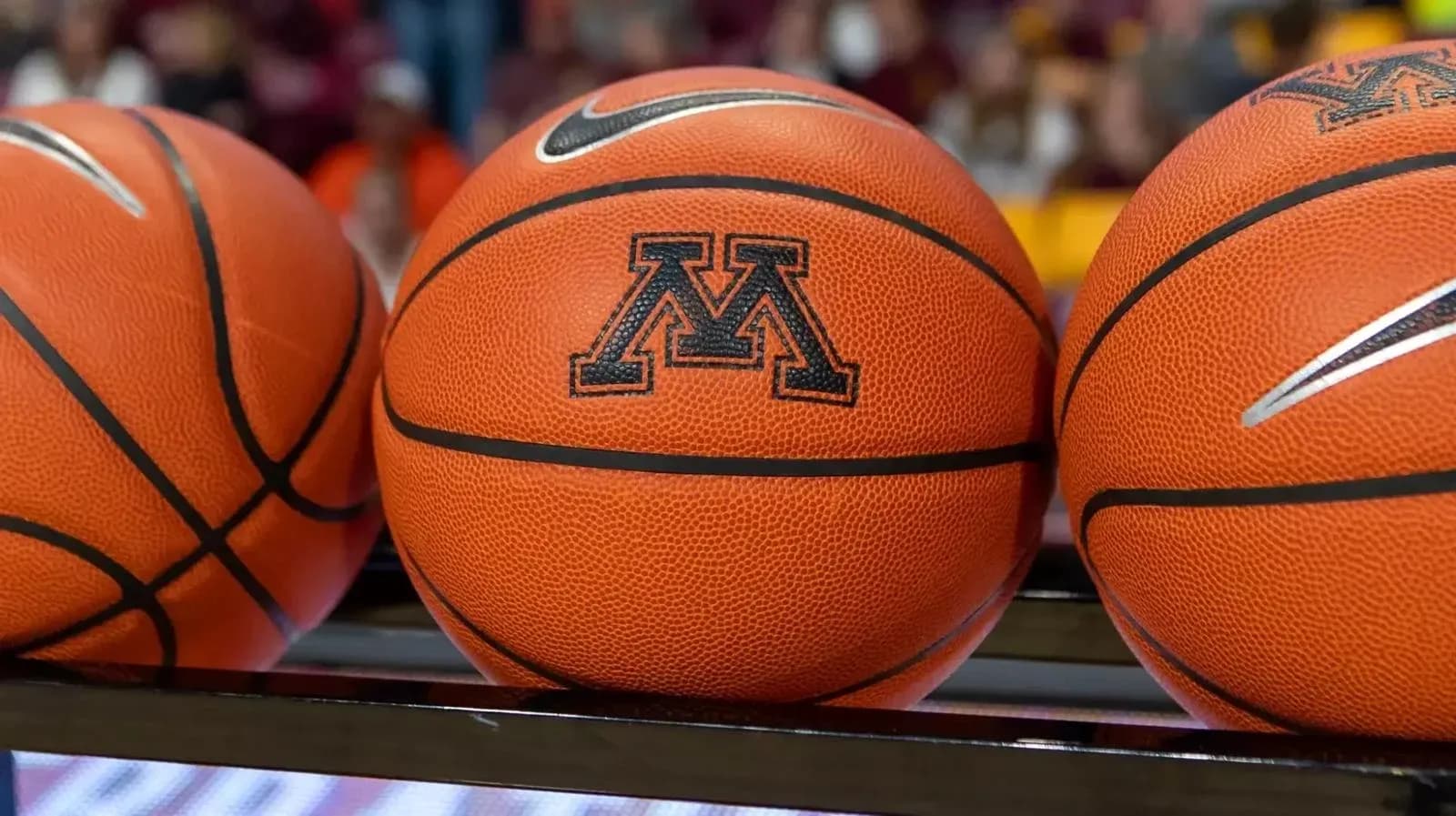Three basketballs with Minnesota logo on bench