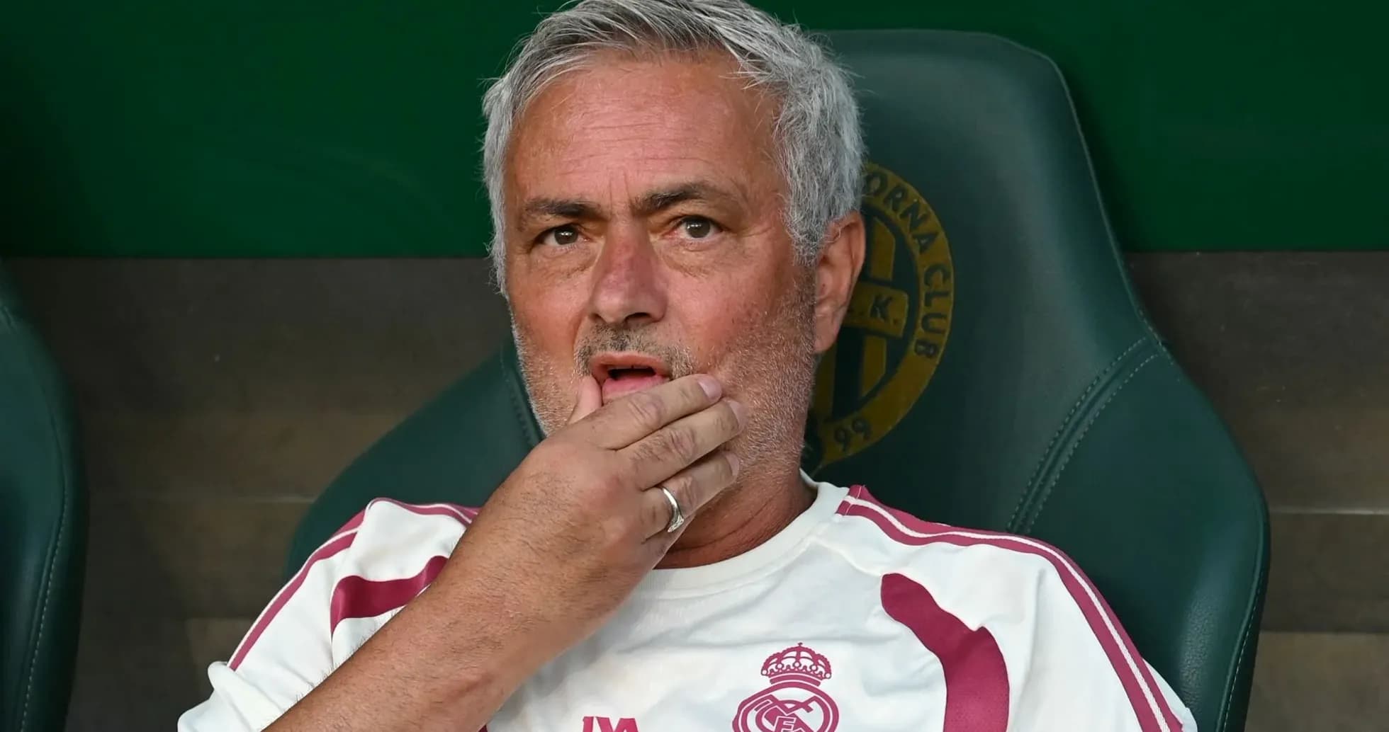 Coach sitting on bench during match, hand on face