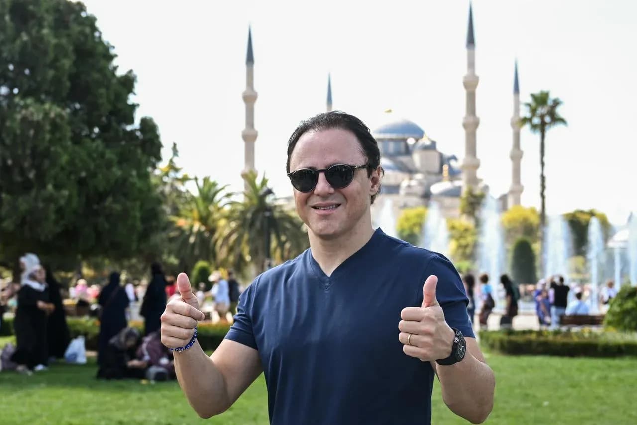 Person giving thumbs up in front of mosque