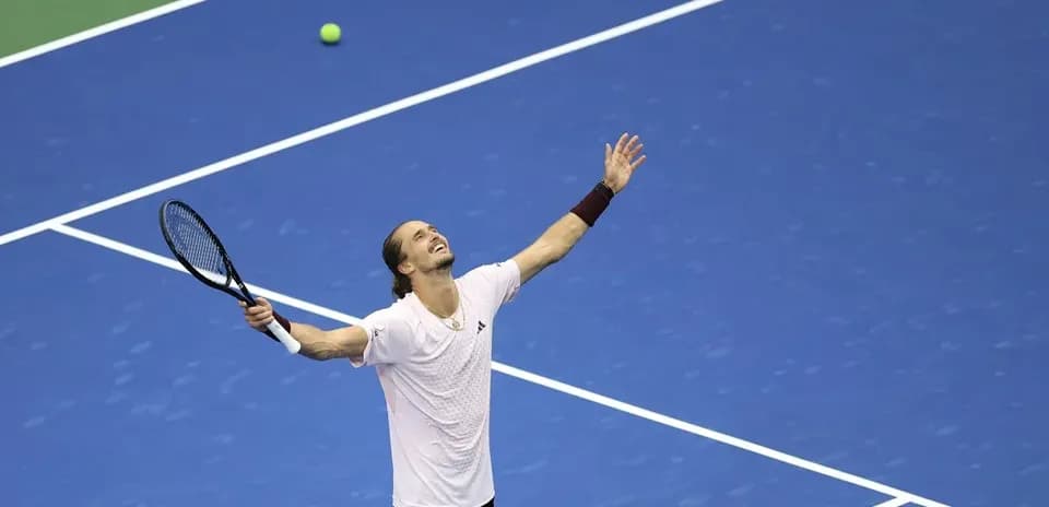 Tennis player celebrating on blue court with racket
