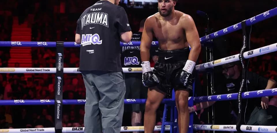 Boxer resting on stool with trainer during match