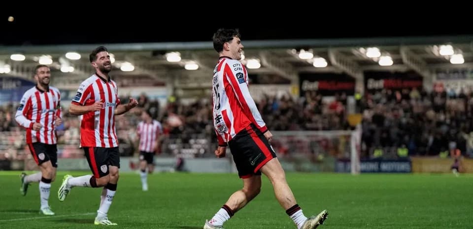 Player celebrating a goal with teammates on pitch