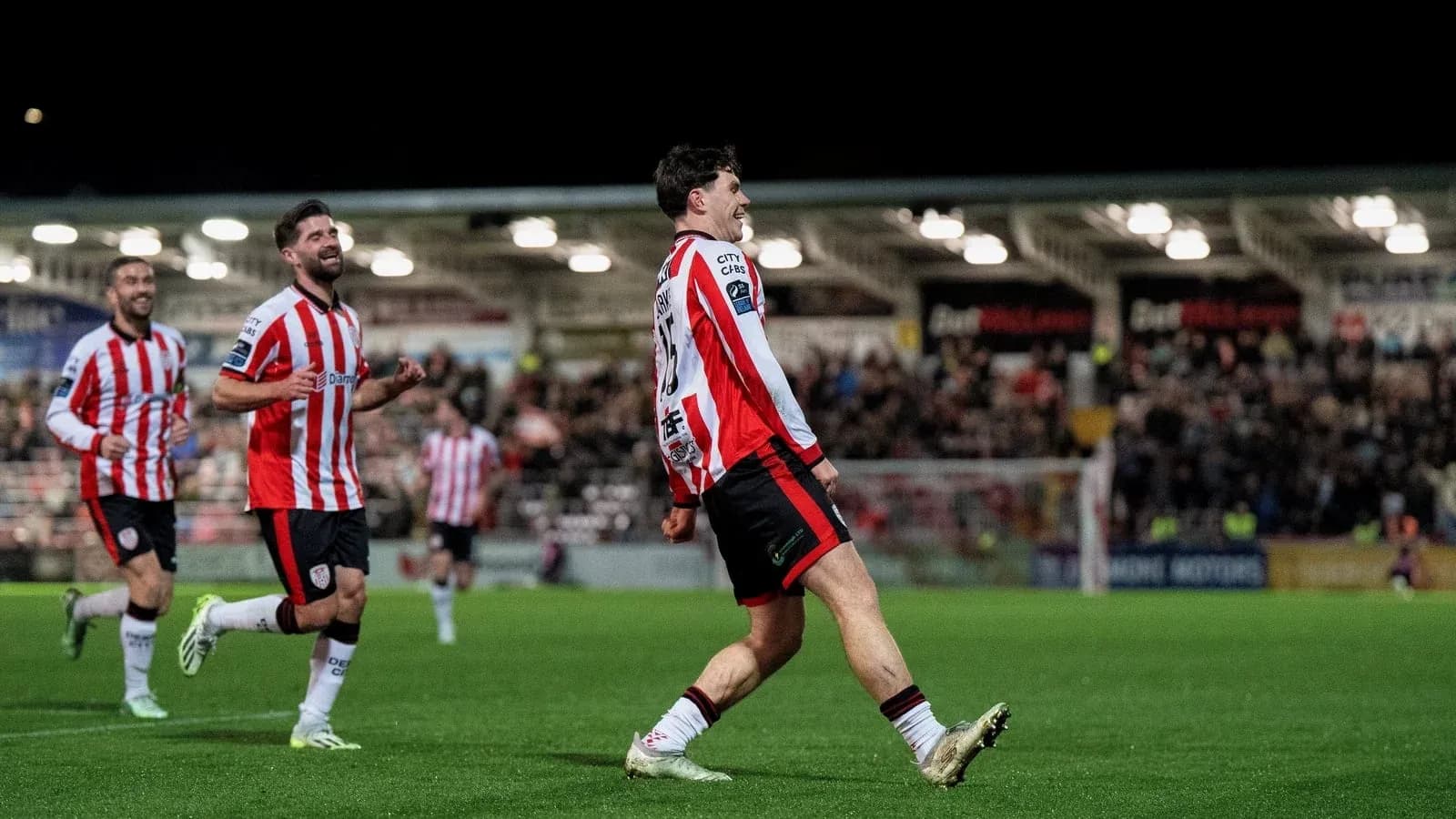 Player celebrating a goal with teammates on pitch