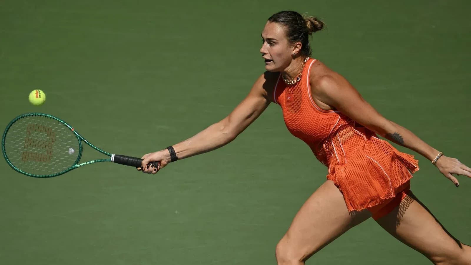 Player reaching for a tennis ball with racket