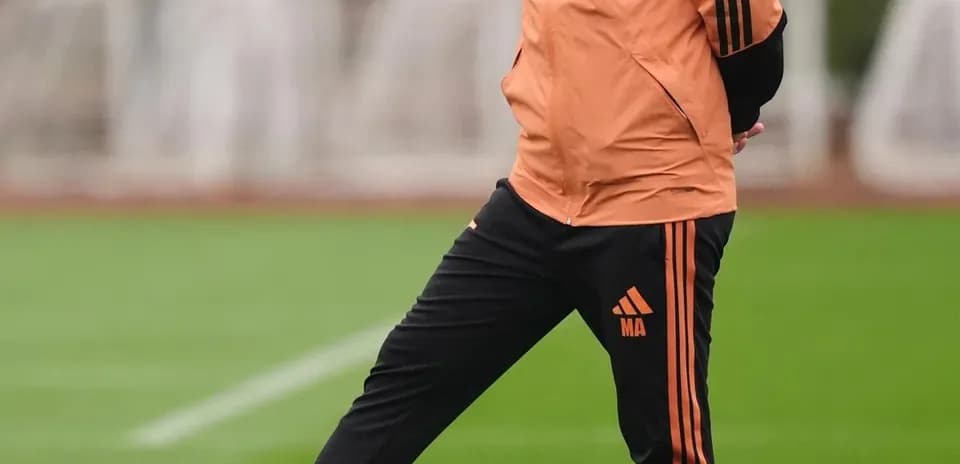 Coach standing on training pitch with football