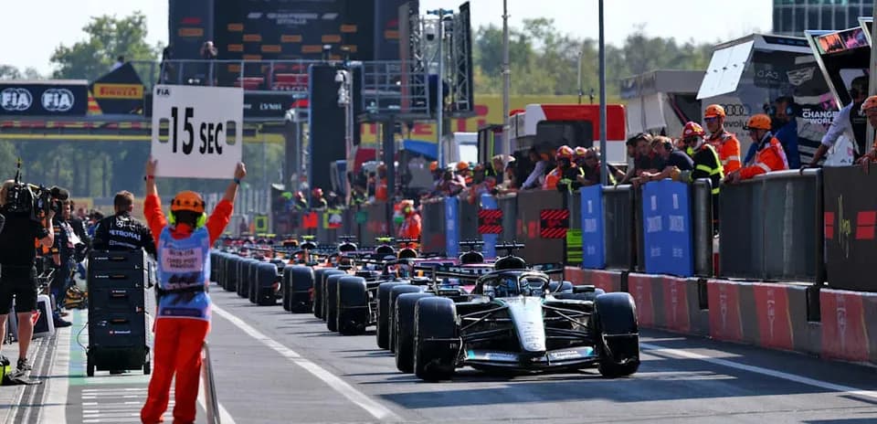 Race cars lined up in pit lane with penalty sign