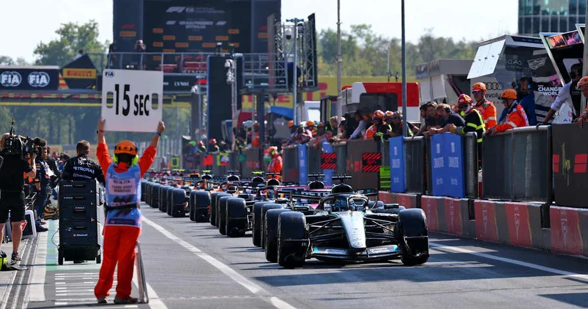 Race cars lined up in pit lane with penalty sign