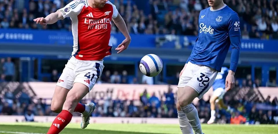 Arsenal player kicking ball near Everton opponent