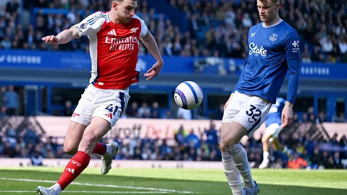 Arsenal player kicking ball near Everton opponent