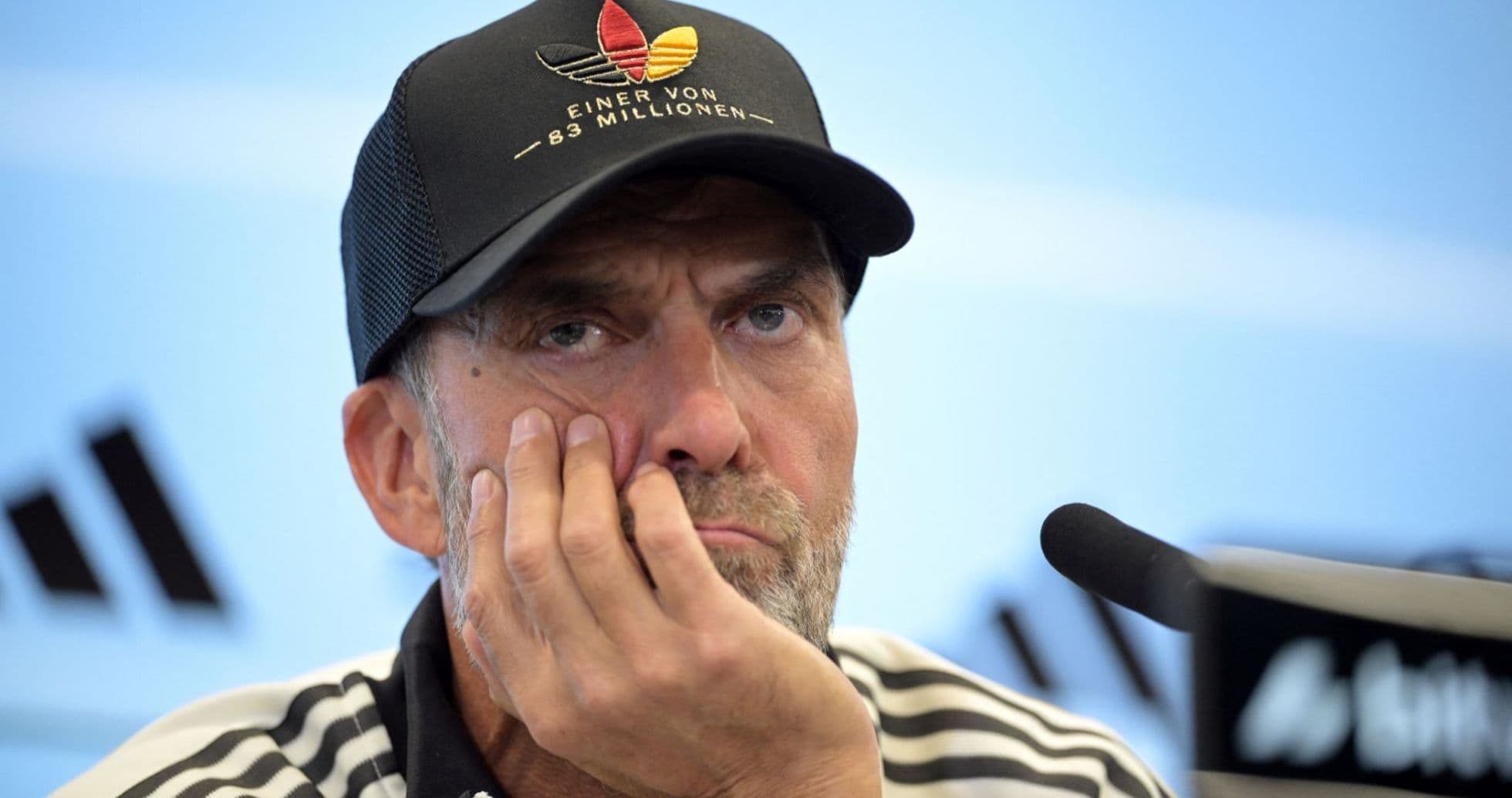 Coach at press conference with hand on face Coach at press conference with hand on face