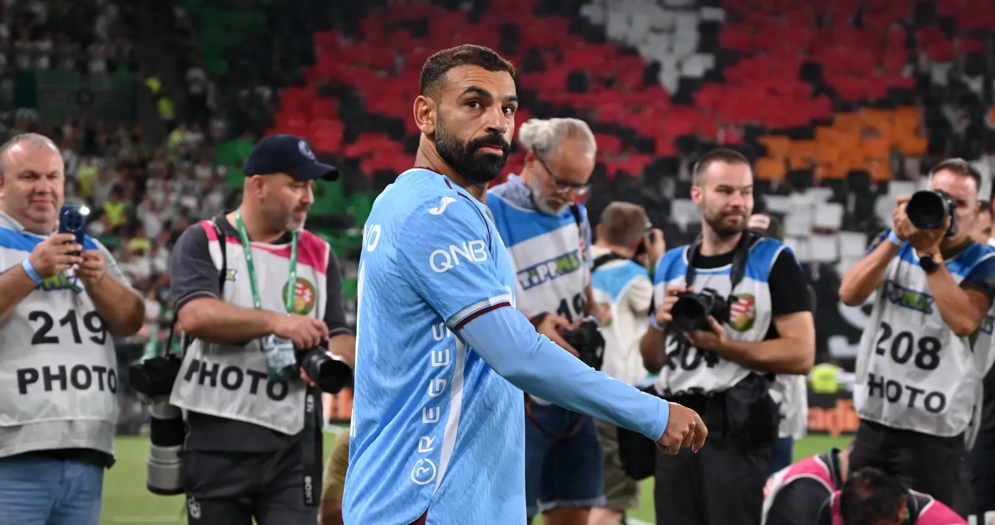 Player walking past photographers on the pitch Player walking past photographers on the pitch