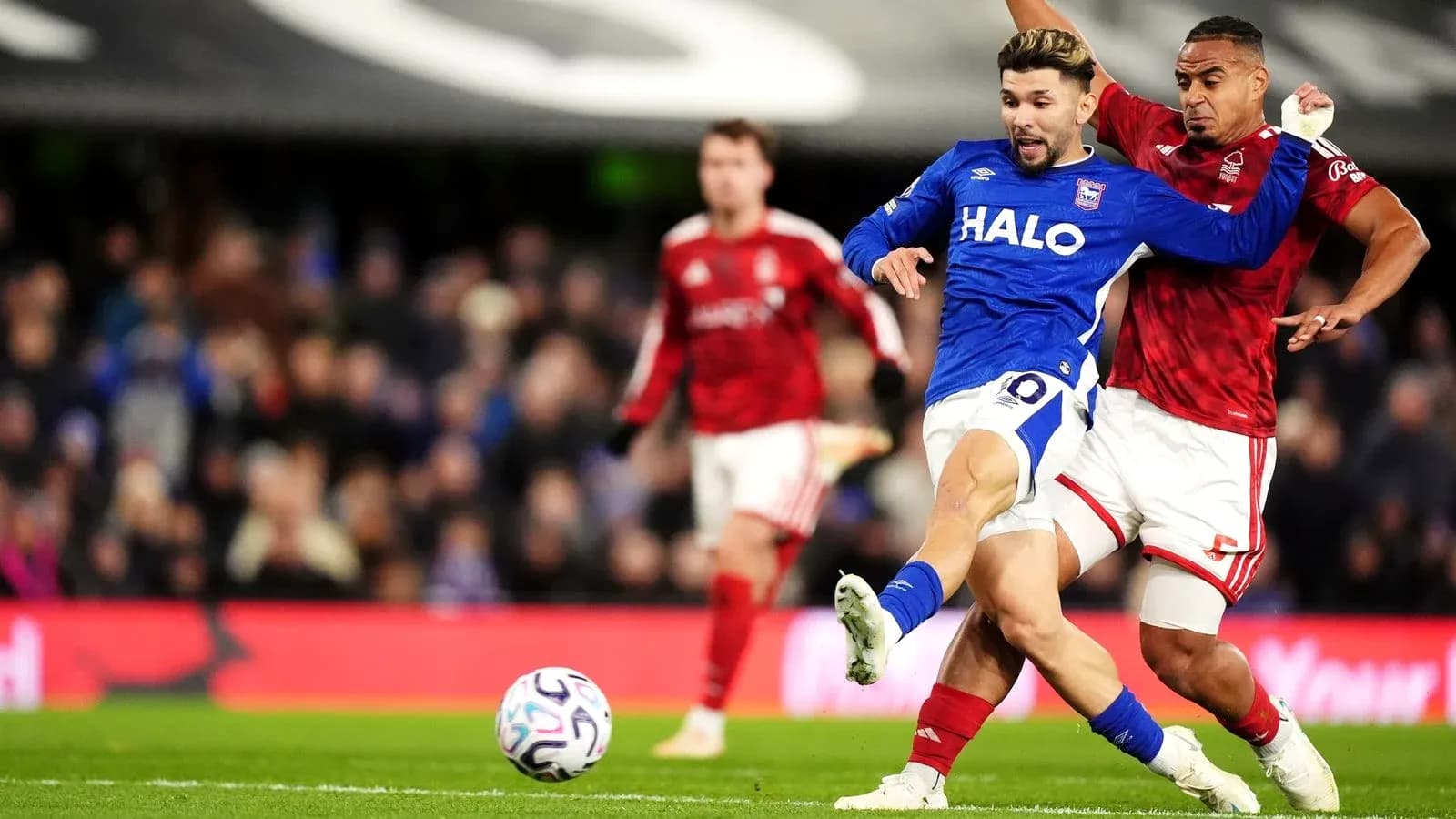 Player in blue jersey challenged by opponent in red Player in blue jersey challenged by opponent in red