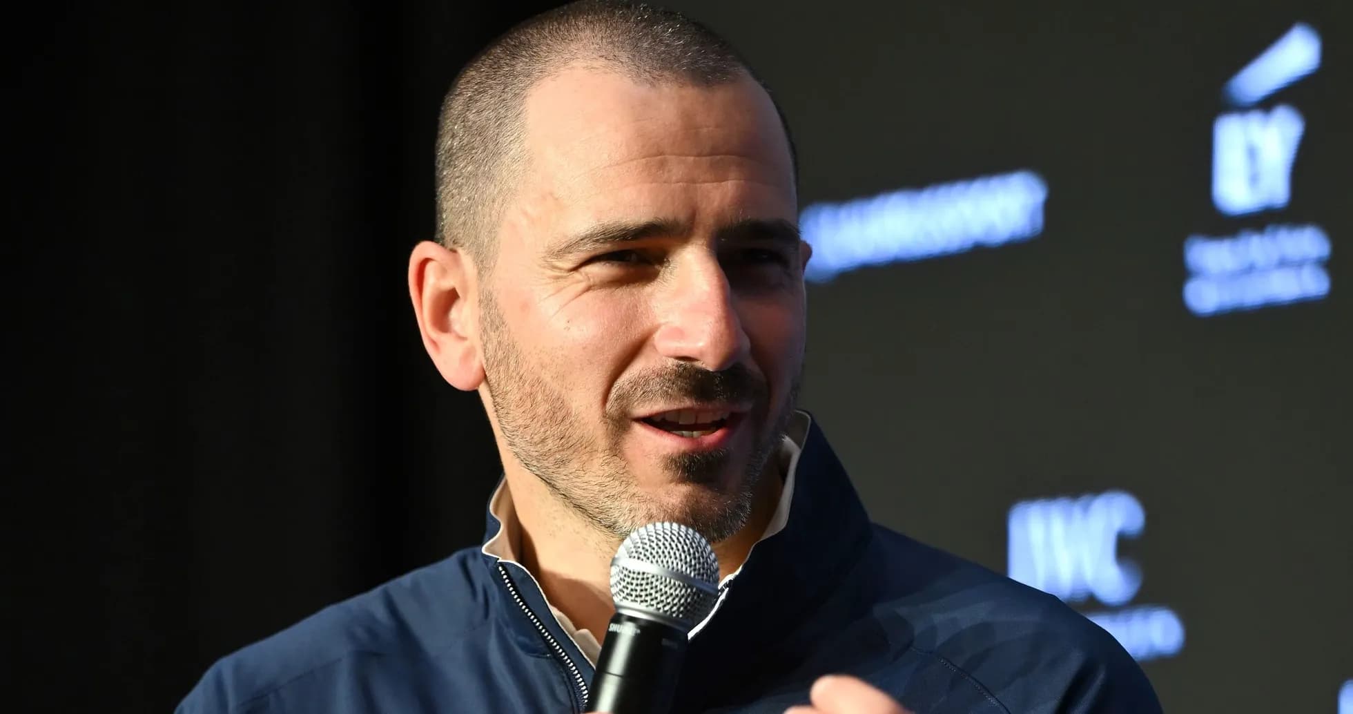 Person speaking into microphone at event Person speaking into microphone at event