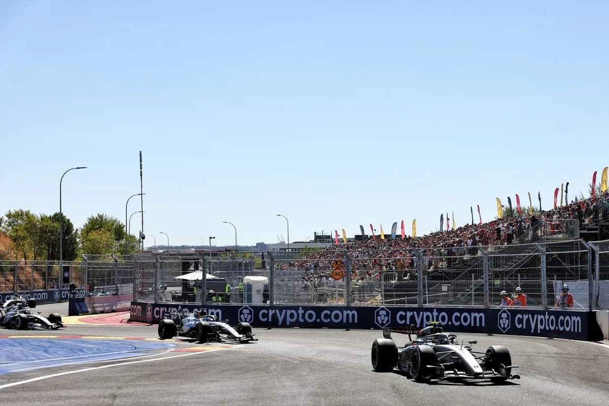 Formula 1 cars racing on track with spectators in background Formula 1 cars racing on track with spectators in background