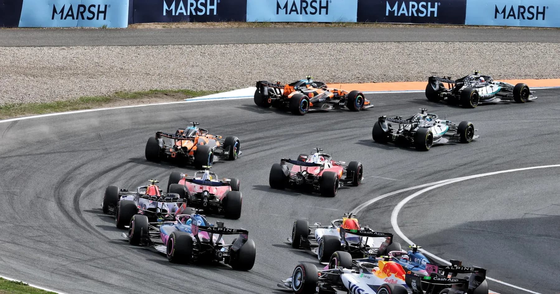 Formula 1 cars racing around a curve on track Formula 1 cars racing around a curve on track