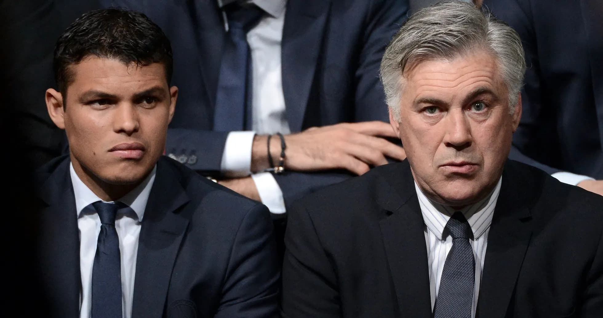Two men in suits seated at an event Two men in suits seated at an event