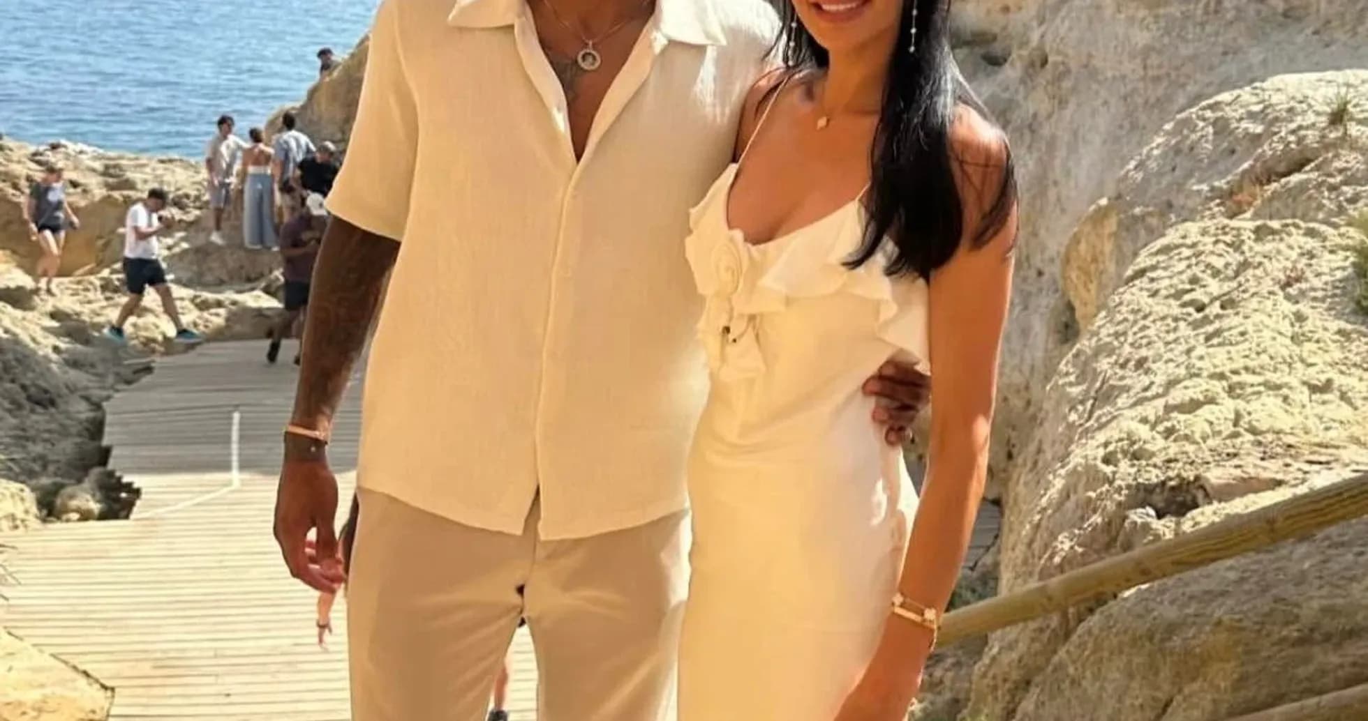 Couple posing by rocky seaside in summer attire Couple posing by rocky seaside in summer attire