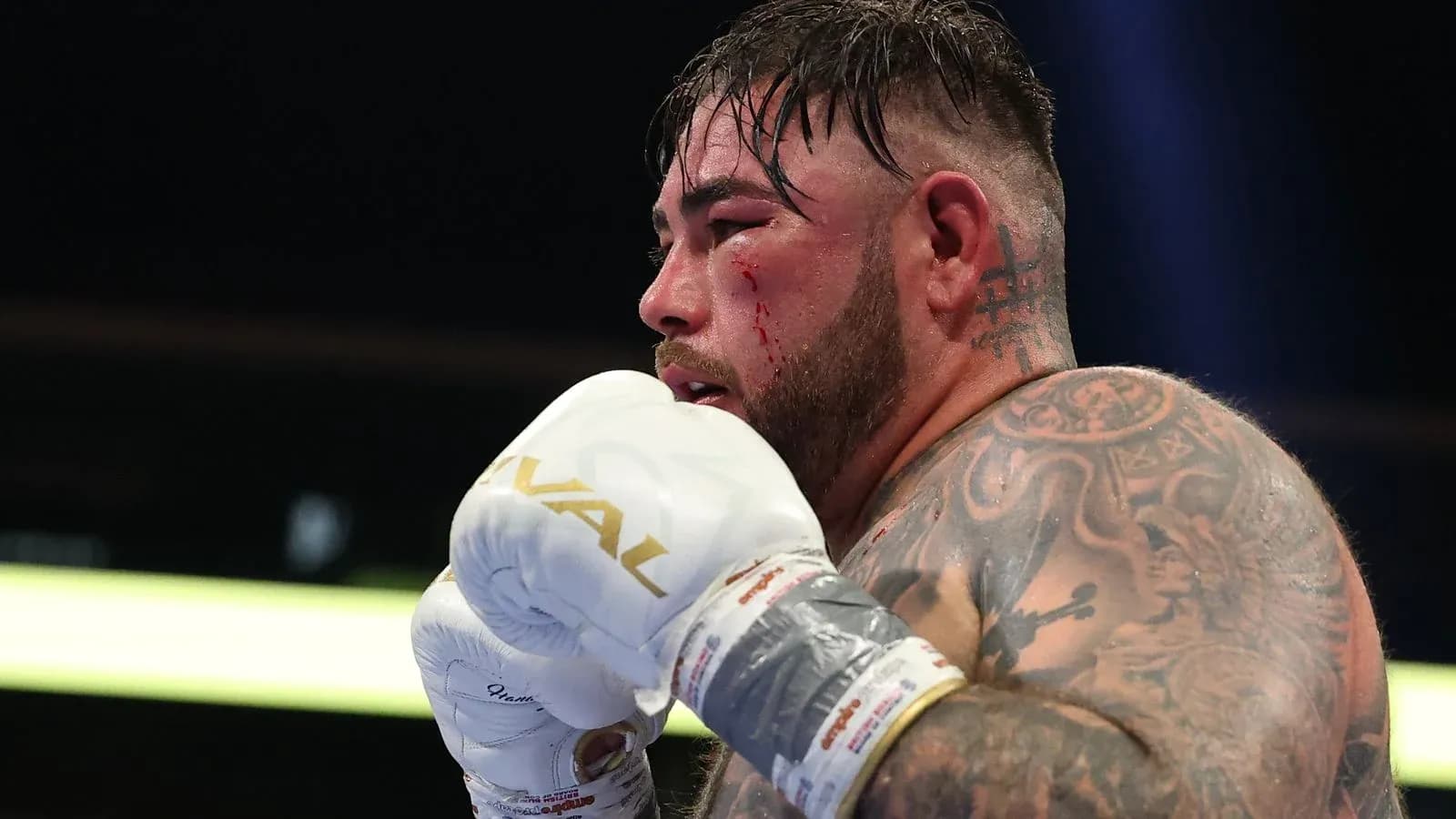 Boxer with tattoos and blood on face in ring Boxer with tattoos and blood on face in ring