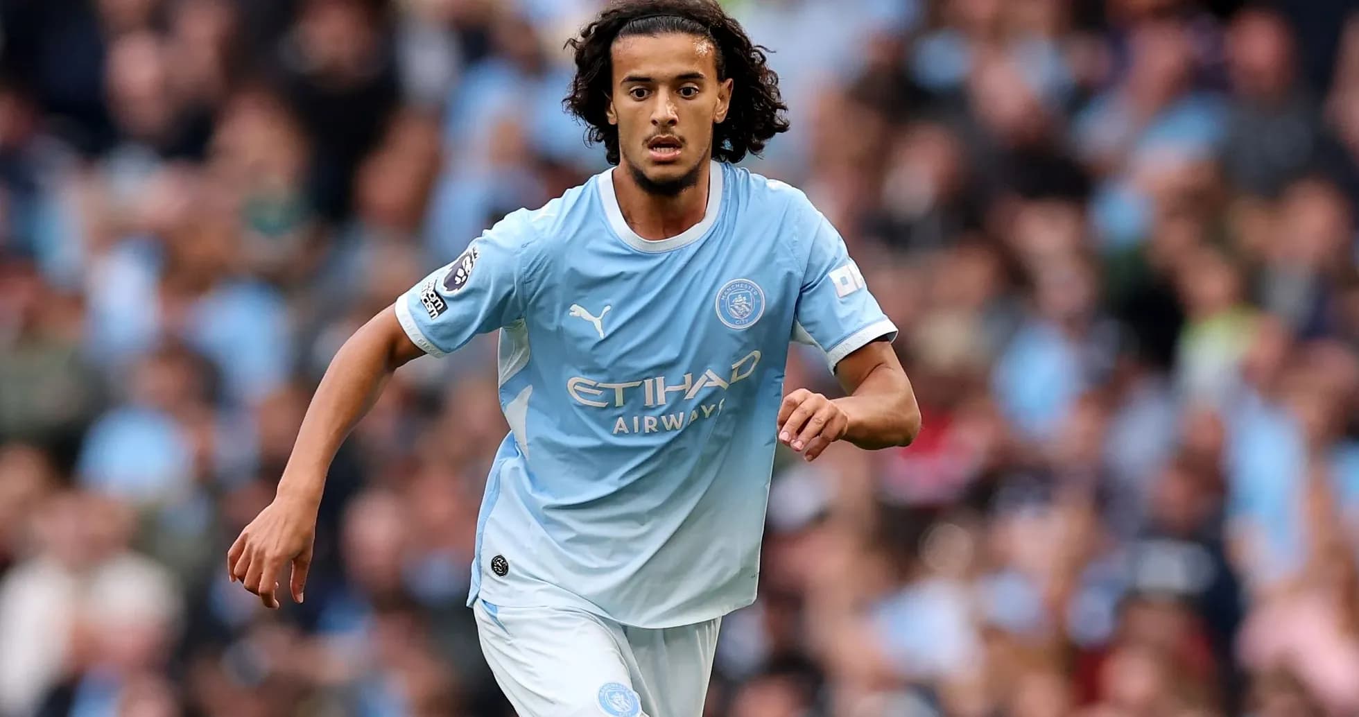 Player in light blue kit running on the pitch Player in light blue kit running on the pitch