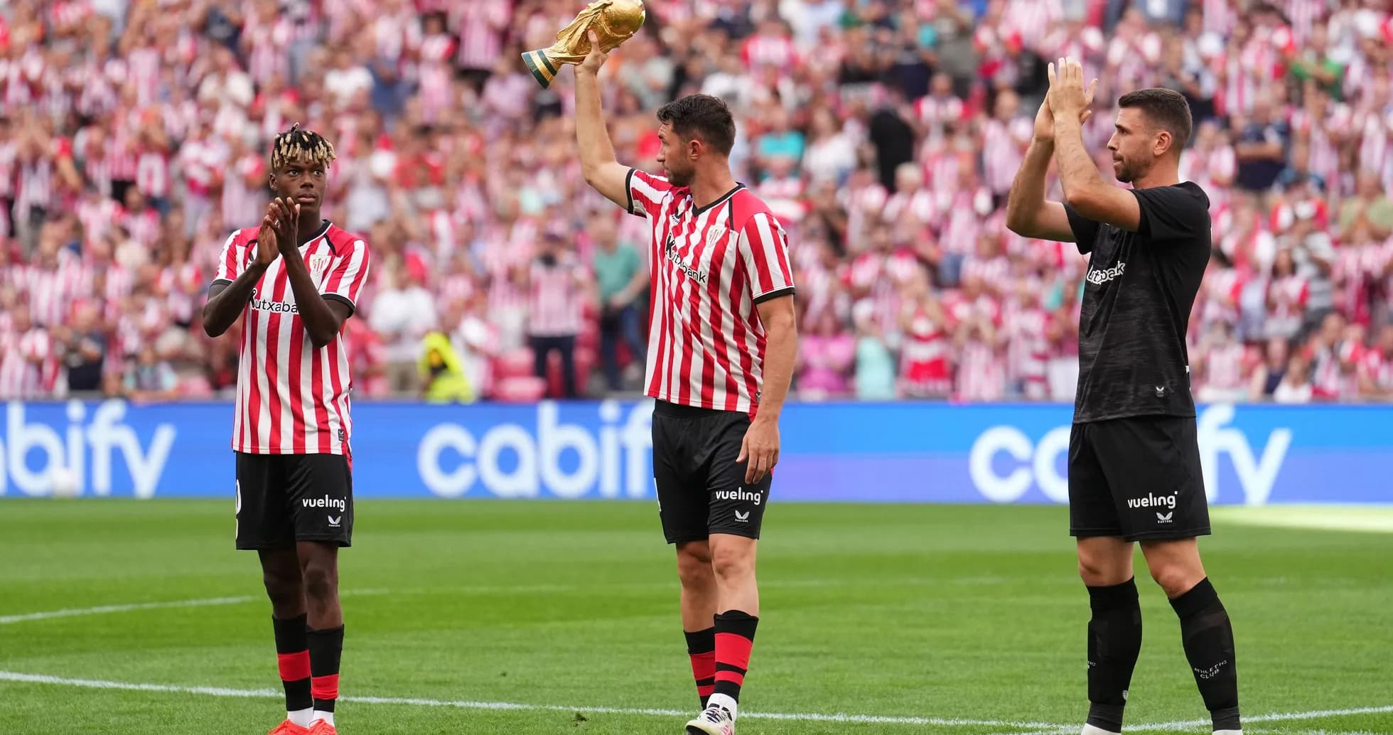 Players celebrating with trophy in front of fans Players celebrating with trophy in front of fans