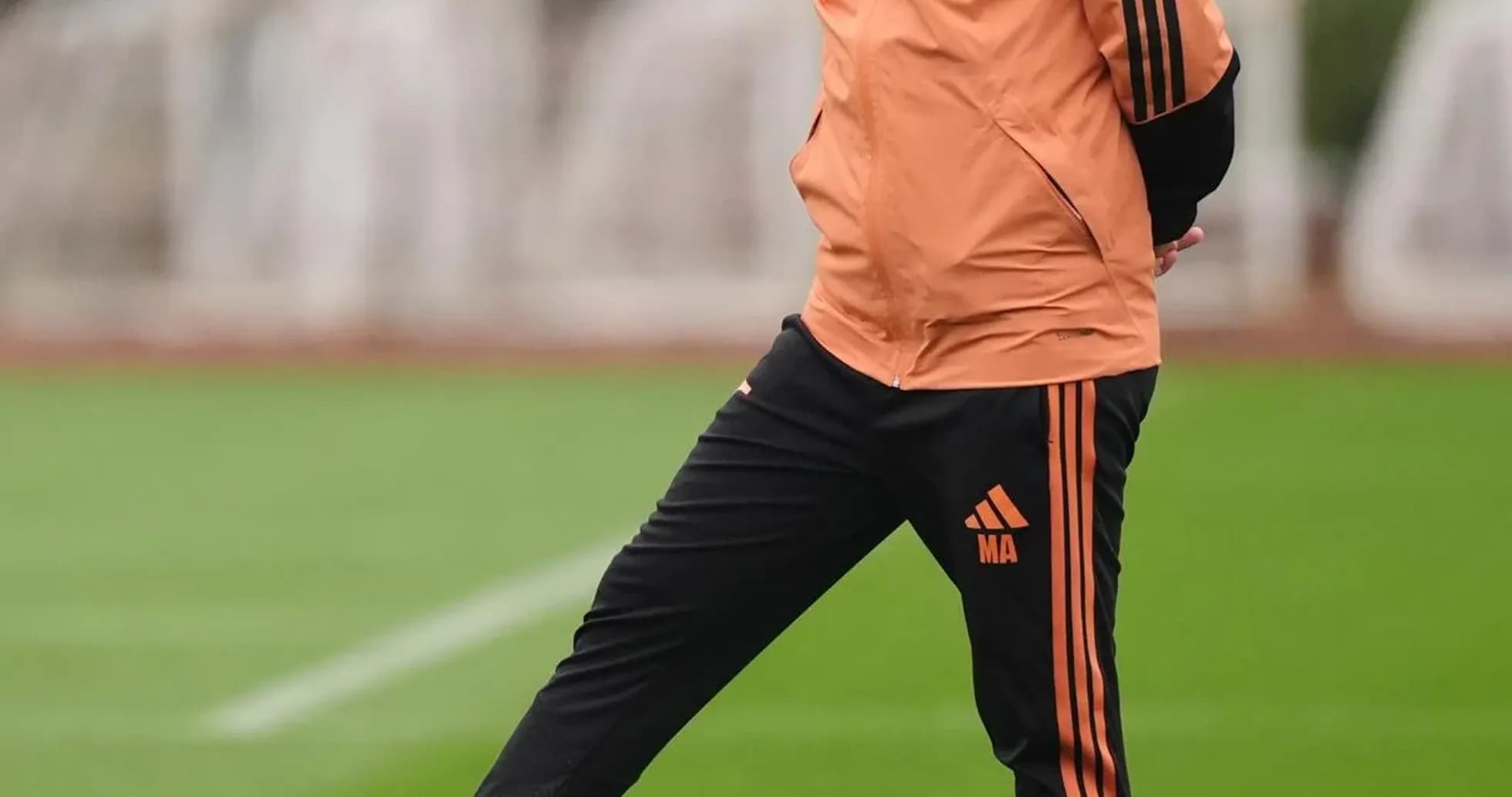 Coach standing on training pitch with football Coach standing on training pitch with football